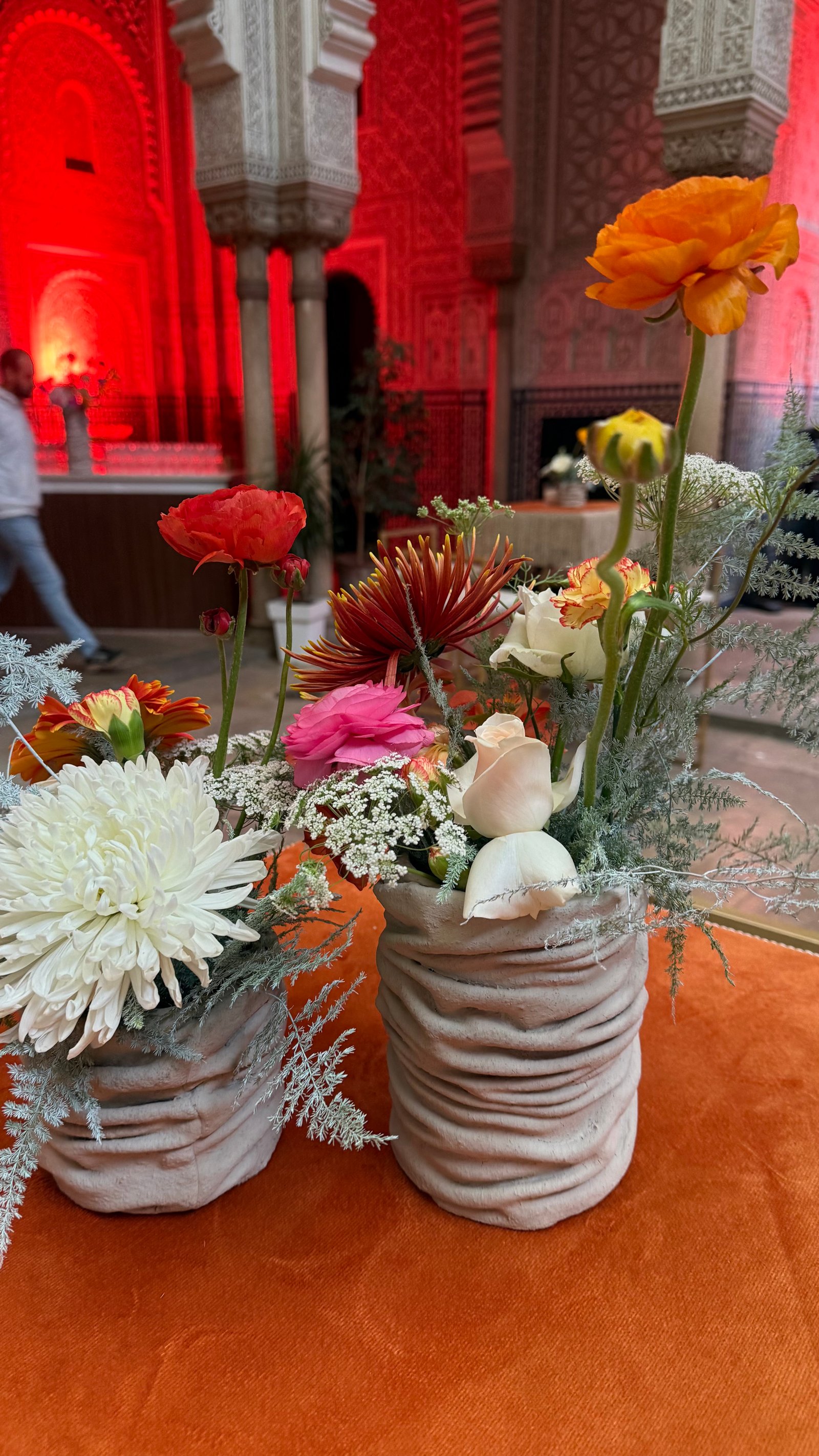 Corporate event for Orange at the Mahkama du Pacha in Habous, Casablanca — orange linens, terracotta vases with ranunculus and gerbera, candlelight and carved Moorish arches, produced by SBAI Events Production