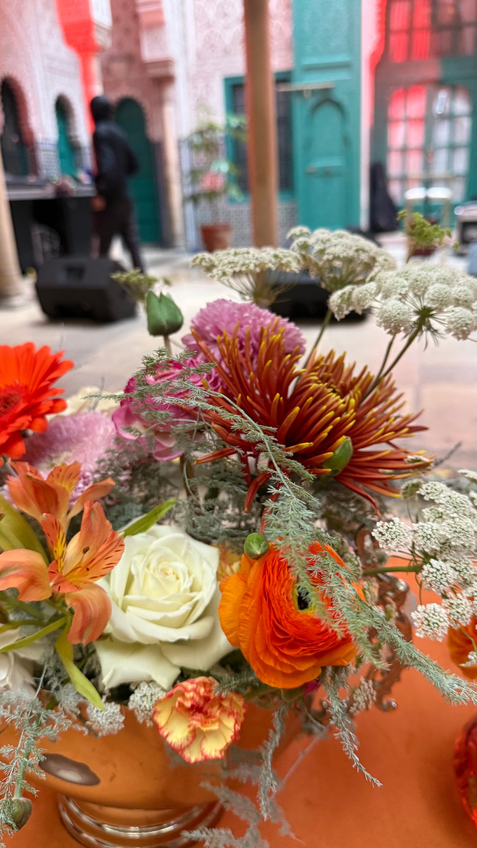 Corporate event for Orange at the Mahkama du Pacha in Habous, Casablanca — orange linens, terracotta vases with ranunculus and gerbera, candlelight and carved Moorish arches, produced by SBAI Events Production