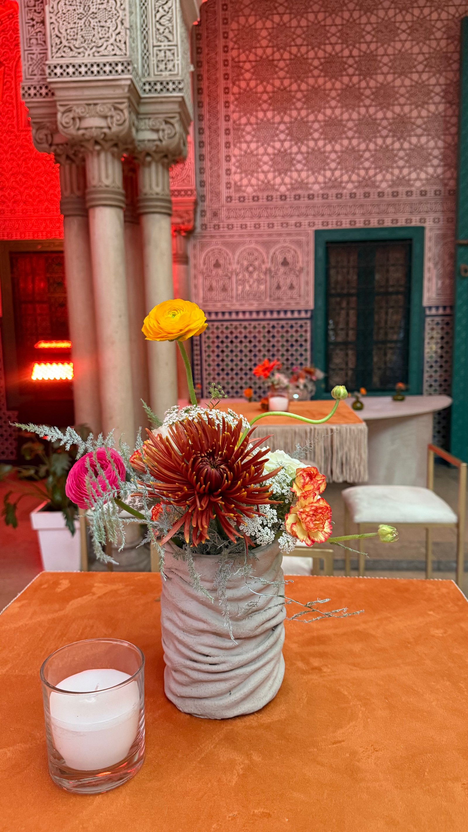Corporate event for Orange at the Mahkama du Pacha in Habous, Casablanca — orange linens, terracotta vases with ranunculus and gerbera, candlelight and carved Moorish arches, produced by SBAI Events Production