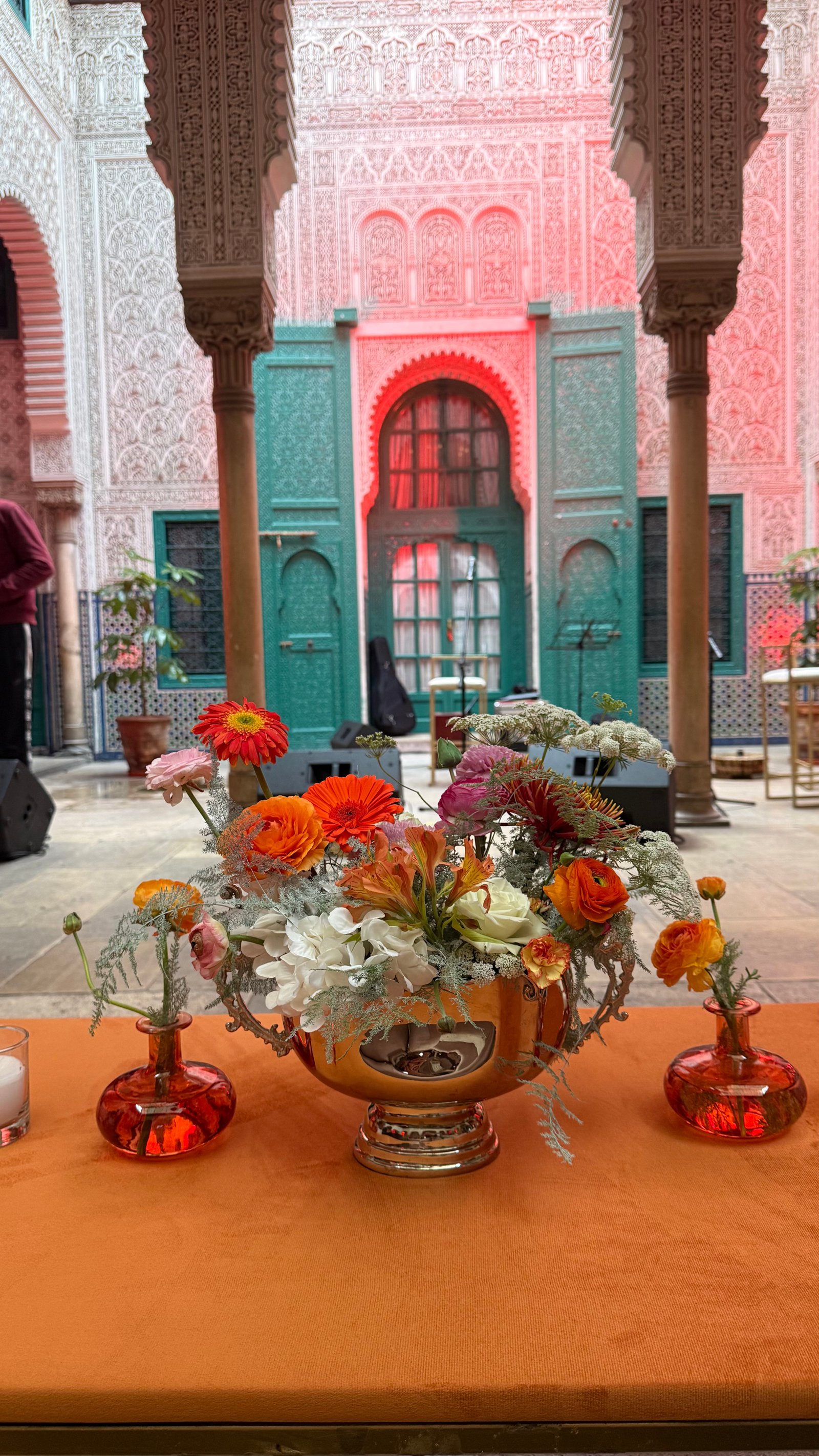 Corporate event for Orange at the Mahkama du Pacha in Habous, Casablanca — orange linens, terracotta vases with ranunculus and gerbera, candlelight and carved Moorish arches, produced by SBAI Events Production