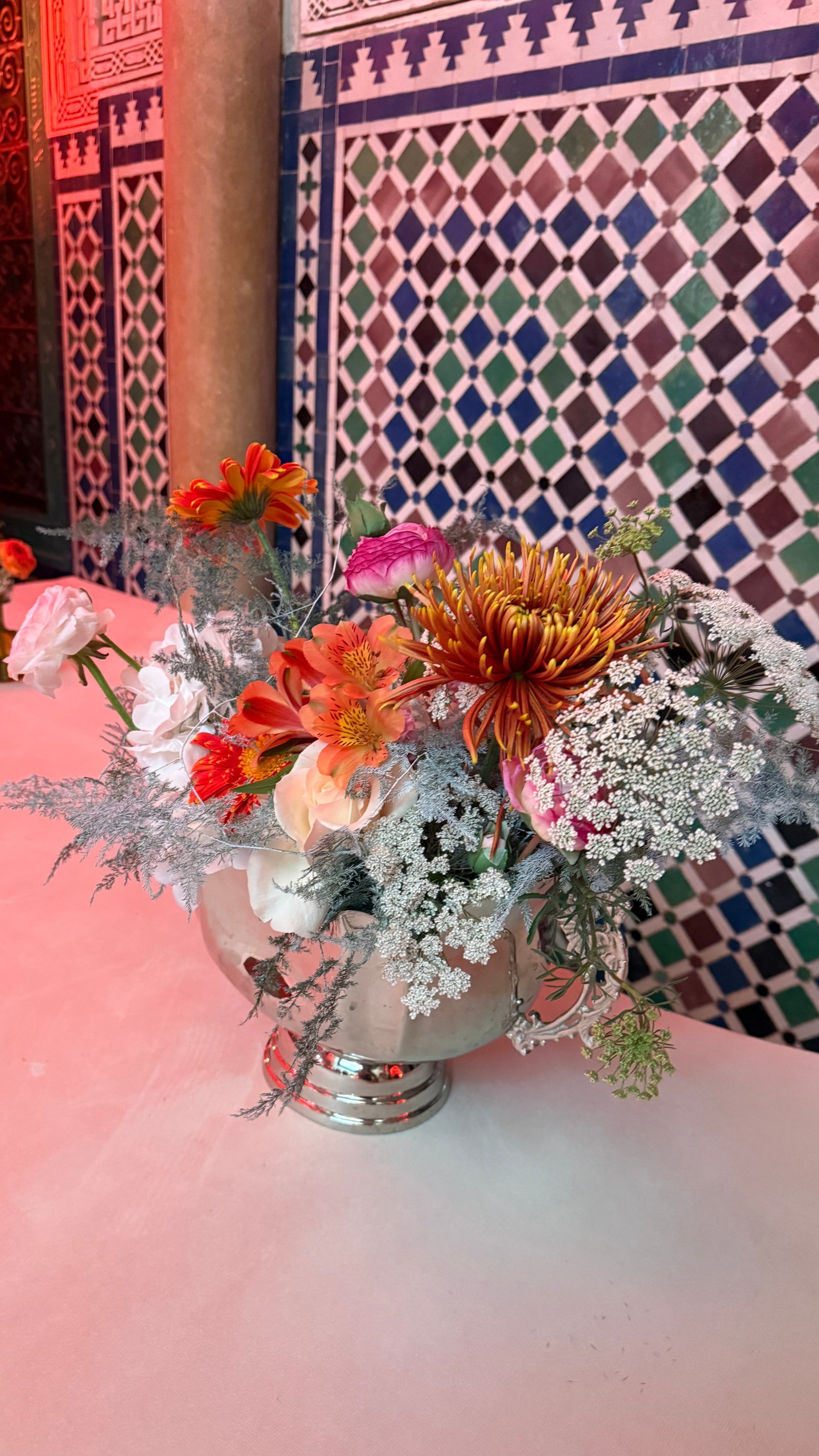 Corporate event for Orange at the Mahkama du Pacha in Habous, Casablanca — orange linens, terracotta vases with ranunculus and gerbera, candlelight and carved Moorish arches, produced by SBAI Events Production