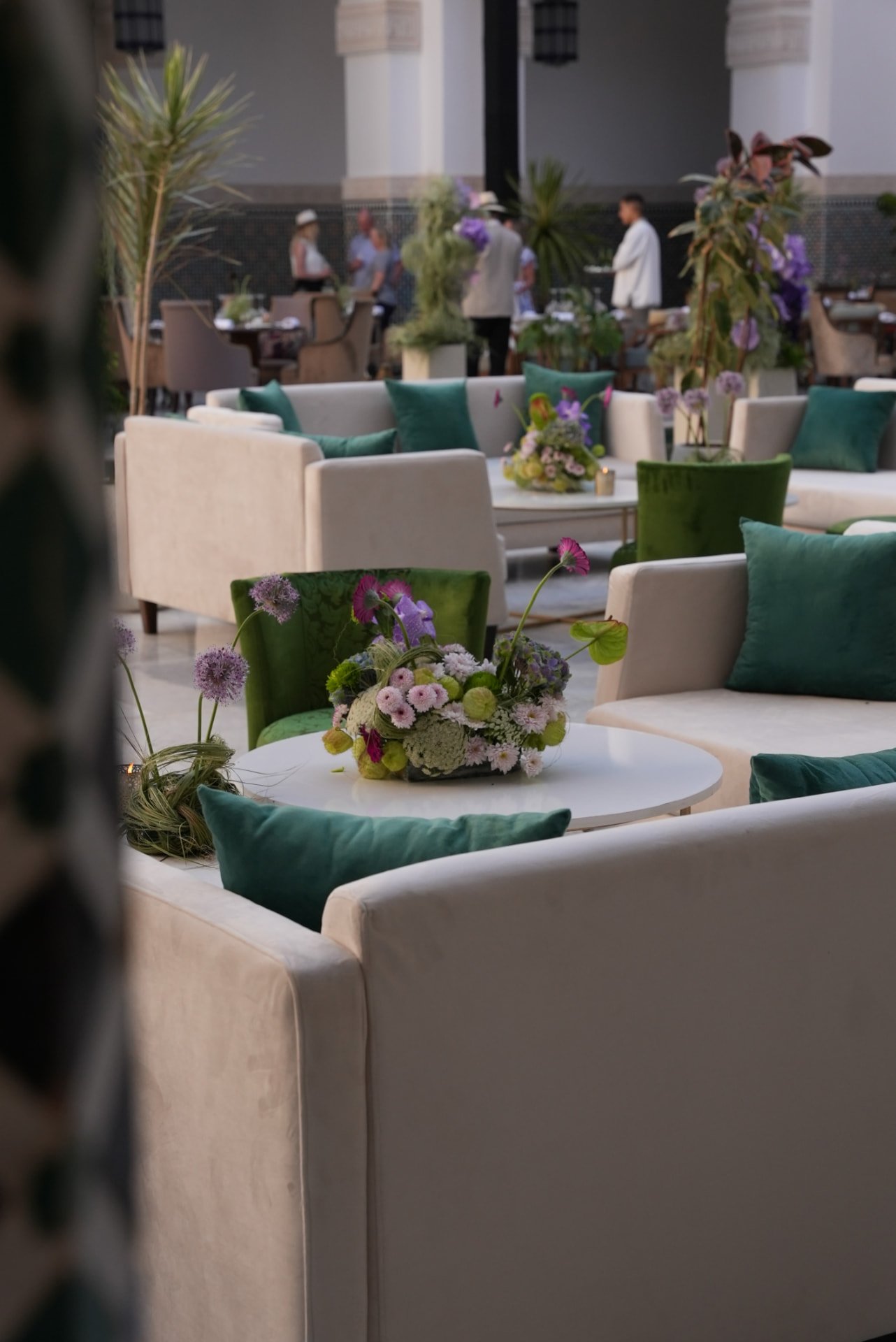 Gala Dinner Vegetal Garden at the patio of the Oberoi Marrakech — purple vanda orchids and anthuriums on white plinths above the emerald reflecting pool, ivory lounges and brass lanterns, produced by SBAI Events Production
