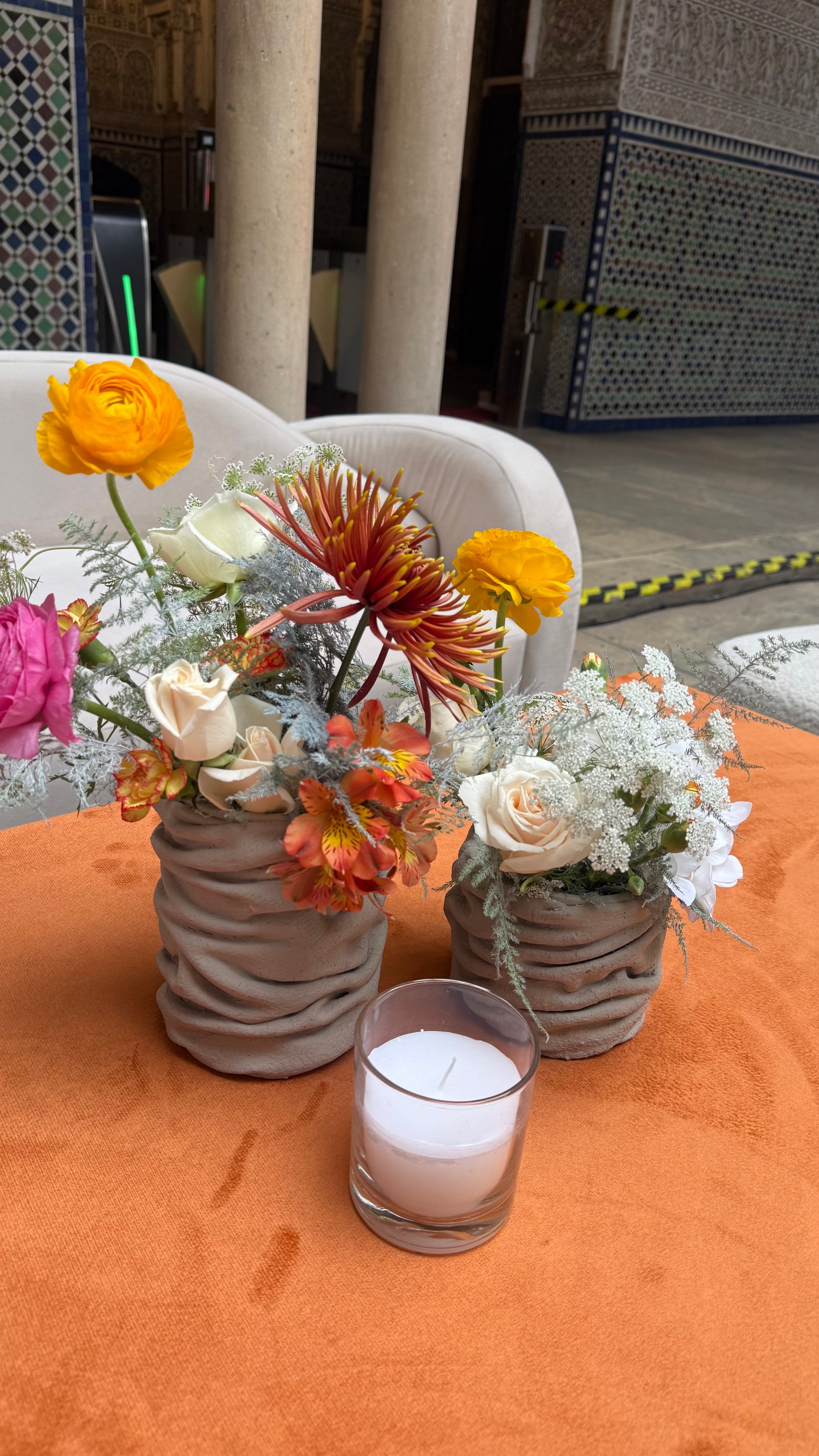 Corporate event for Orange at the Mahkama du Pacha in Habous, Casablanca — orange linens, terracotta vases with ranunculus and gerbera, candlelight and carved Moorish arches, produced by SBAI Events Production