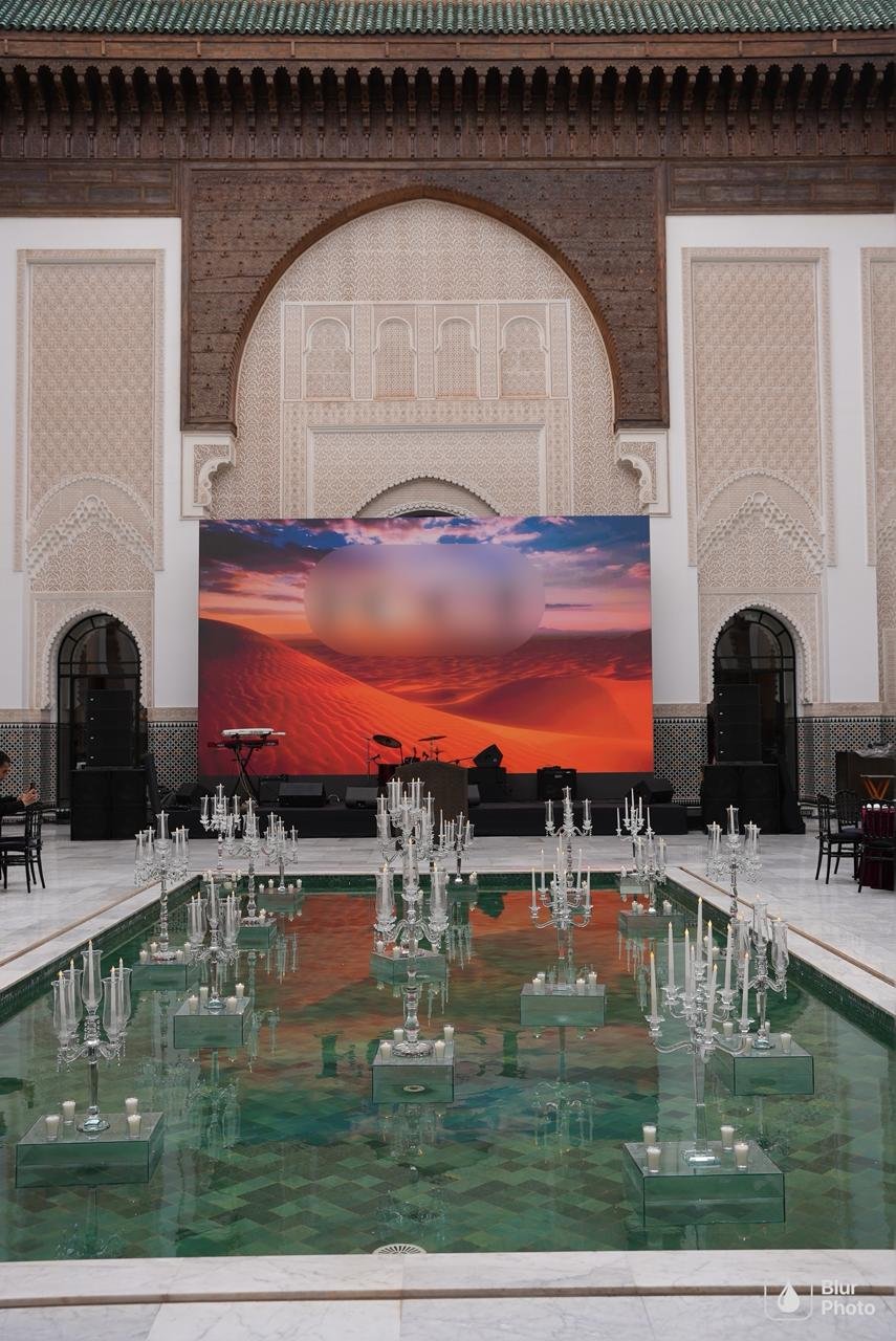 Crystal candelabras and floating candles reflected in a green zellige pool at a luxury Marrakech gala, designed by SBAI Events Production